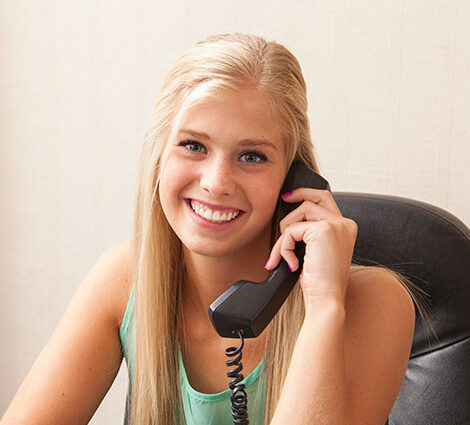 A picture of a woman holding a phone. We're here to help 24/7